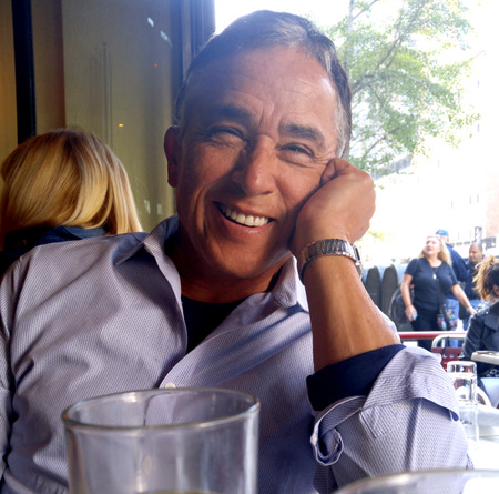 An image of Patrick Pacheco, with grey hair and a blue patterned shirt, smiling.